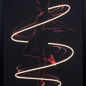Ballerina Light Trail LED wall decor featuring a ballerina in crimson silhouette en pointe with extended arm wrapped in a sweeping white-gold LED spiral on a dark background, framed dance wall decor
